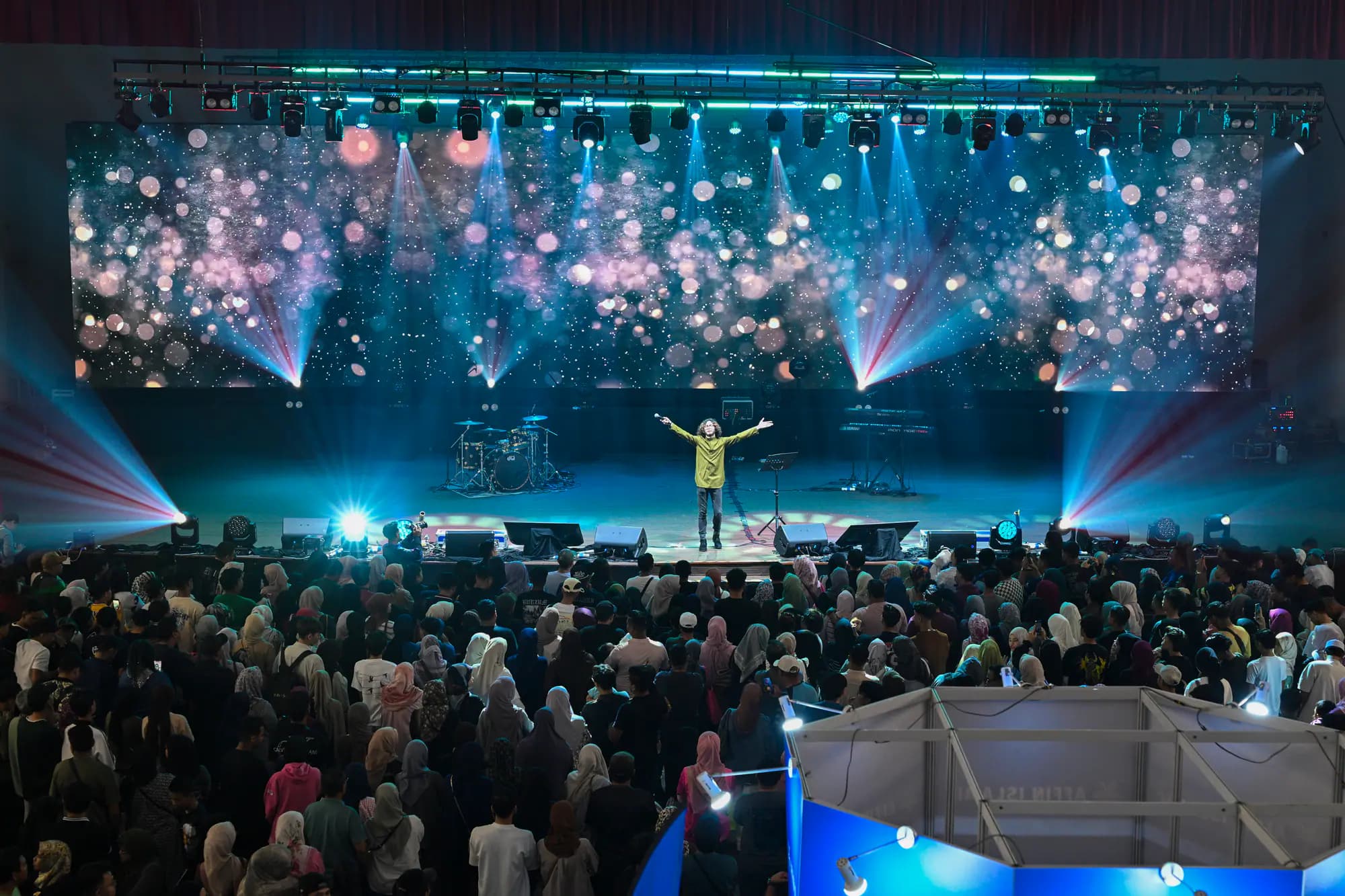 A packed hall facing the concert stage under coloured lights in Penang